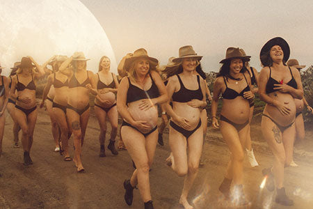 Laughing pregnant women walking down a road barefoot